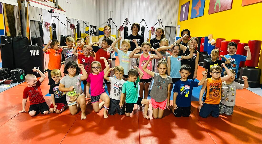 Several summer camp students pose for a picture with their fists in the air
