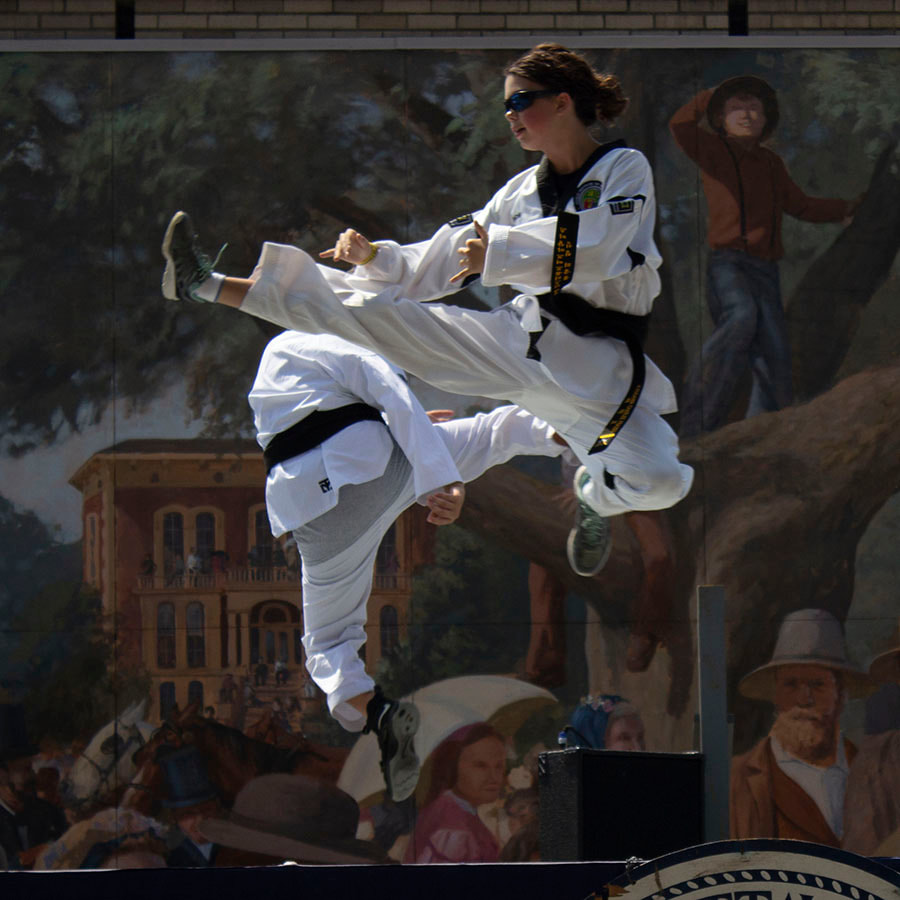 Two black belts performing simultaneous flying side kicks.