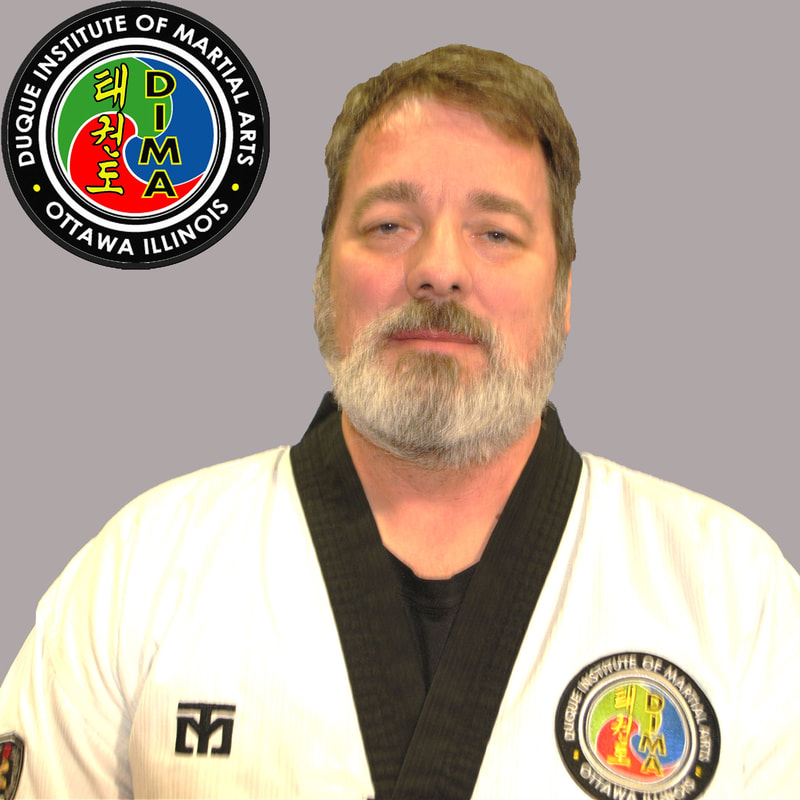 Man in taekwondo uniform with grey hair and beard.