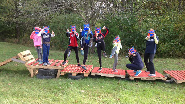 Eight taekwondo students wear ninja masks while they pose on an obstacle course.