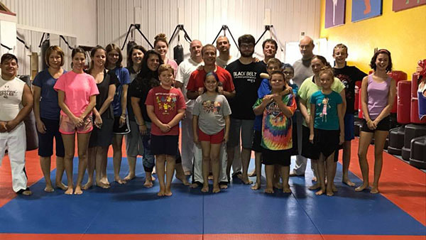 Martial arts master and large group of self defense students pose.