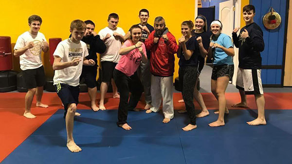 Martial arts master and self defense students pose in fighting stance.