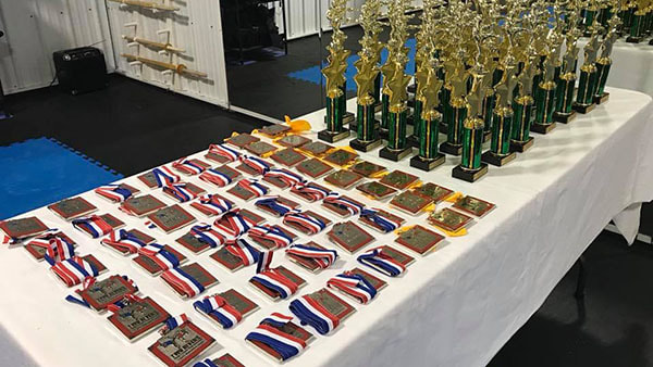 Several trophies and medals laid out on a table in preparation for a tournament.
